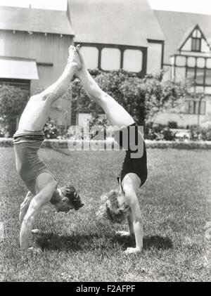 Side view of young couple doing handstands in yard (OLVI008 OU348 F) Stock Photo