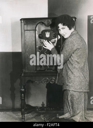 Woman adjusting volume on 1920s radio (OLVI008 OU320 F) Stock Photo