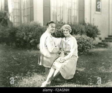 Happy couple reading outdoors (OLVI008 OU086 F) Stock Photo