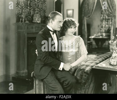 Couple sitting on edge of couch (OLVI007 OU857 F) Stock Photo