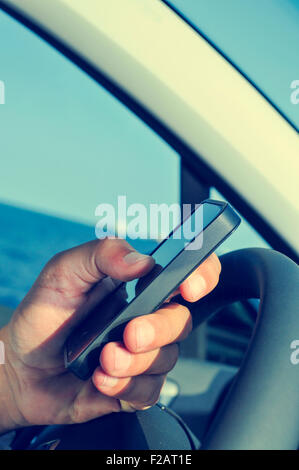 closeup of a man using a smartphone while driving a car Stock Photo