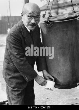 Japanese Ex-Premier Hideki Tojo, at Omori Prison Camp for suspected war criminals. Nov. 9, 1945. After Japan's defeat he shot himself, but received medical care and recovered. He is drawing water from a storage bag. (CSU 2015 11 1701) Stock Photo