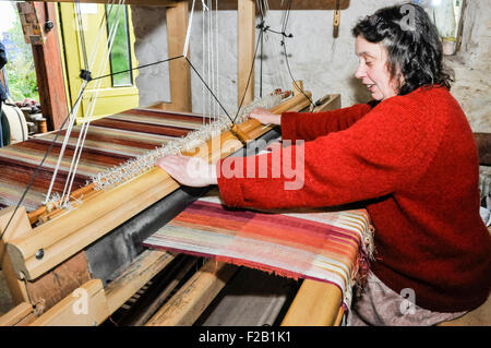 A woman weaves linen textile using a traditional hand loom Stock Photo