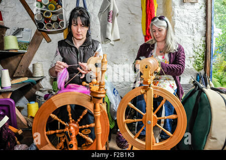 Two women spin wool using traditional spinning wheels. Stock Photo