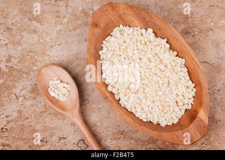 White grated corn kernels in wooden bowl with spoon on marble table. Selective focus. Tonning effect Stock Photo