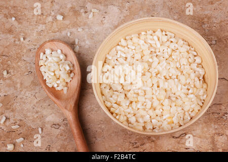 White grated corn kernels in wooden bowl with spoon on marble table. Selective focus. Toning effect Stock Photo