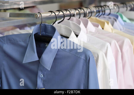 Men's plaid shirts in different colors on hangers in a retail shop Stock Photo