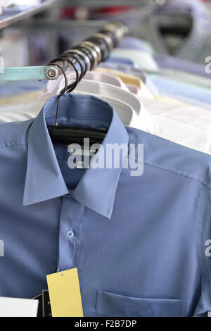 Men's plaid shirts in different colors on hangers in a retail shop Stock Photo