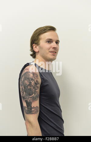 Garden City, New York, USA. September 13, 2015. KRISTJAN VALDIMARSSON, from Akureyri, Iceland, displays the tattoo just completed by his brother Gunnar Valdimarsson, at the United Ink Flight 915 Tattoo convention at the Cradle of Aviation Museum in Long Island. The shirt sleeve is taped up away from tattoo, which has a traditional Nordic theme, with a bearded Viking man's head and Viking ship. Credit:  Ann E Parry/Alamy Live News Stock Photo