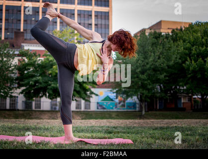 Attractive young woman practicing yoga in the park Stock Photo