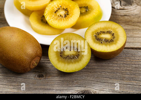 Close up of freshly sliced golden kiwi on rustic wood. Stock Photo