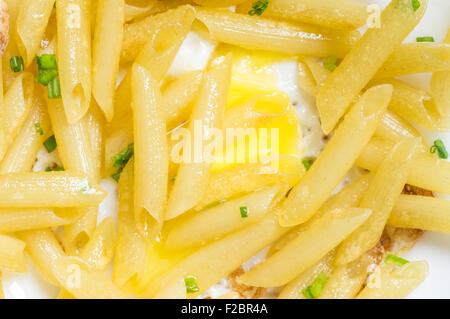Italian penne pasta on a plate with egg closeup top view Stock Photo