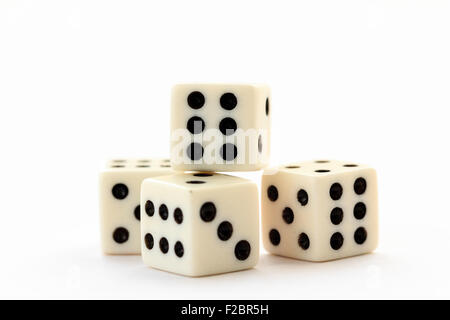 Four white dice with black spots and red single one on illuminated white plain background. Stock Photo