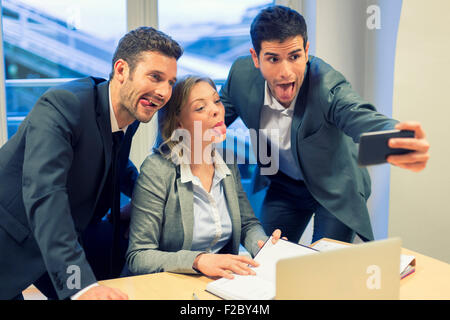 Portrait of three business people making faces while taking a selfie with smartphone Stock Photo