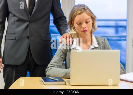 depressed businesswoman using laptop in her office with colleague Stock Photo