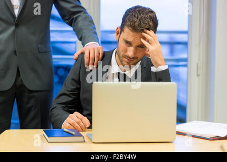frustrated business man using laptop with colleague in his office Stock Photo