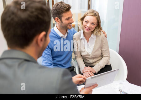 financial advisor using digital tablet and meeting with couple in office Stock Photo
