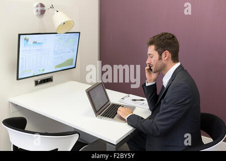 businessman using laptop and cell phone in conference room Stock Photo