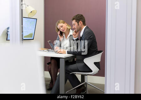 Business colleagues working on laptop in office. Business woman using smartphone Stock Photo