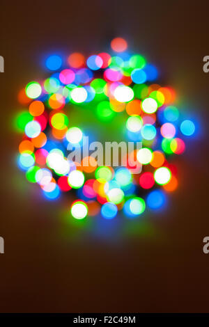 A bright circular multicolor bokeh in the form of a Christmas wreath created by a set of de-focused lights. Stock Photo