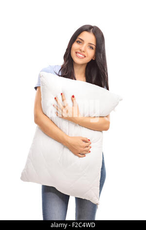 Vertical shot of a young woman hugging a pillow and looking at the camera isolated on white background Stock Photo
