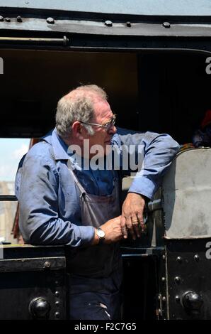 Vintage steam train driver in coal soiled blue overalls in locomotive cab Stock Photo