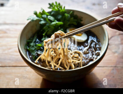 overhead view of ramen with hand holding chop sticks and noodles Stock Photo