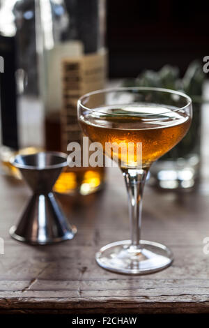 chilled amber cocktail in stemmed glass on rustic wood table Stock Photo