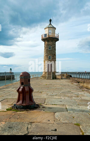 Old capstan and lighthouse on the East Pier of Whitby Harbour, Whitby, Yorkshire, England, UK Stock Photo