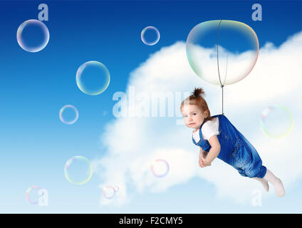Funny child fly on soap bubble, flight creative concept Stock Photo