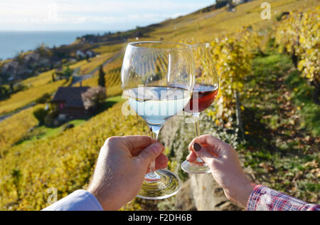 Two hands holding wineglases against vineyards in Lavaux region, Switzerland Stock Photo