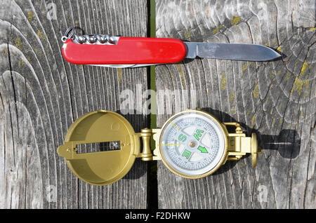 Compass and pocket knife on the wooden background Stock Photo