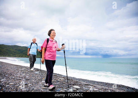 happy senior couple hiking on the coast beach Stock Photo
