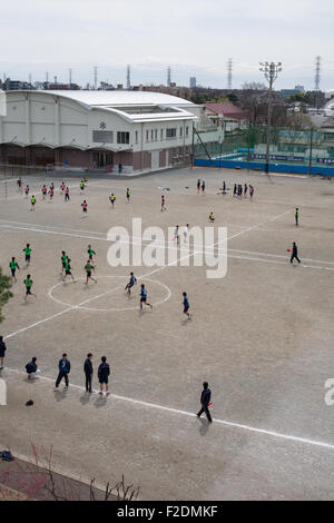 Dirt schoolyard with kids playing soccer football pov from above right open space Stock Photo