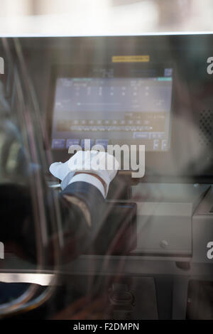 View through glass train drivers hand in white glove with computer display Stock Photo