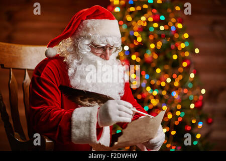 Santa Claus answering Christmas letter by sparkling firtree Stock Photo