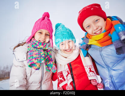 Joyful friends in winterwear looking at camera outdoors Stock Photo