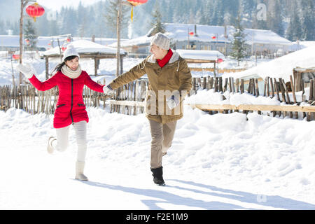 Young couple holding hands running in the snow Stock Photo