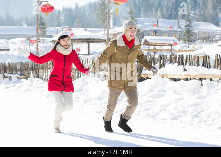 Young couple holding hands running in the snow Stock Photo