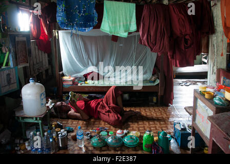 A Buddhist monk reading a book in his room at a monastery in Kyauktan township of Yangon Myanmar, Burma Stock Photo