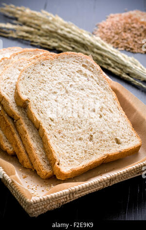 Slices of whole wheat bread in basket on black background. Stock Photo