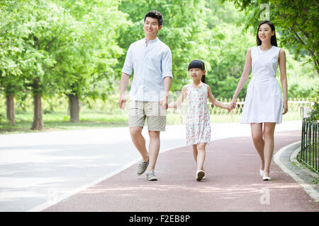 Happy young family walking together in park Stock Photo