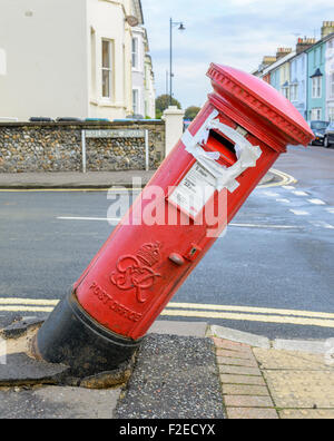 British red pillar box leaning over after an accident. Damaged red letter box toppling over in the UK. Stock Photo