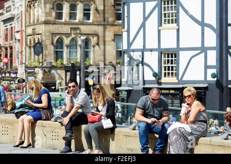 People relaxing in the sun at Manchester city centre's Exchange Square   UK Great Britain British United Kingdom Europe European Stock Photo