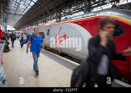 Manchester Piccadilly railway station Virgin logo on a Pendolino train from London   Passengers passing blurred walking to   Man Stock Photo