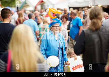ALDI sponsored 10th Bolton Food and Drink Festival 2015  a grandma walks through the crowds with a balloon modelled crown hat on Stock Photo
