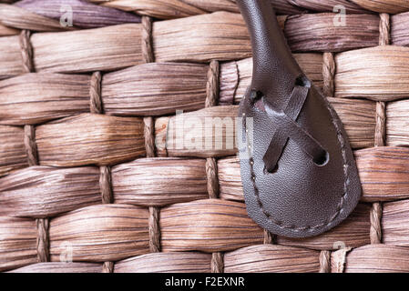 A macro shot of a leather handle stitched into a brown wovel wicker basket. Stock Photo