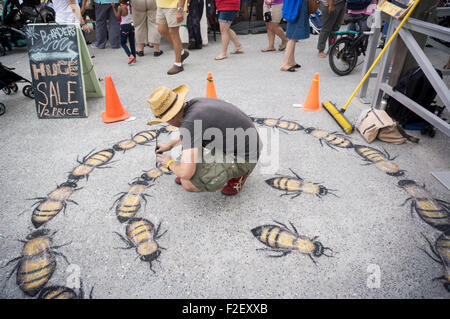 Artist creates a bee-themed sidewalk painting at the the New York City Honey Fest in Rockaway in the borough of Queens in New York on Saturday, September 12, 2015. Visitors participated in honey tastings and purchased honey and honey-themed goods from the various vendors.   (© Richard B. Levine) Stock Photo