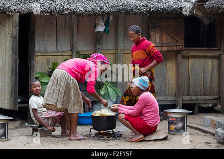 Malagasy family cooking maniok in front of traditional wooden house in rural village, Vatovavy-Fitovinany, Madagascar, Africa Stock Photo