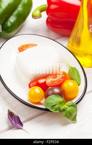 Mozzarella, tomatoes, basil and olive oil on wooden table Stock Photo